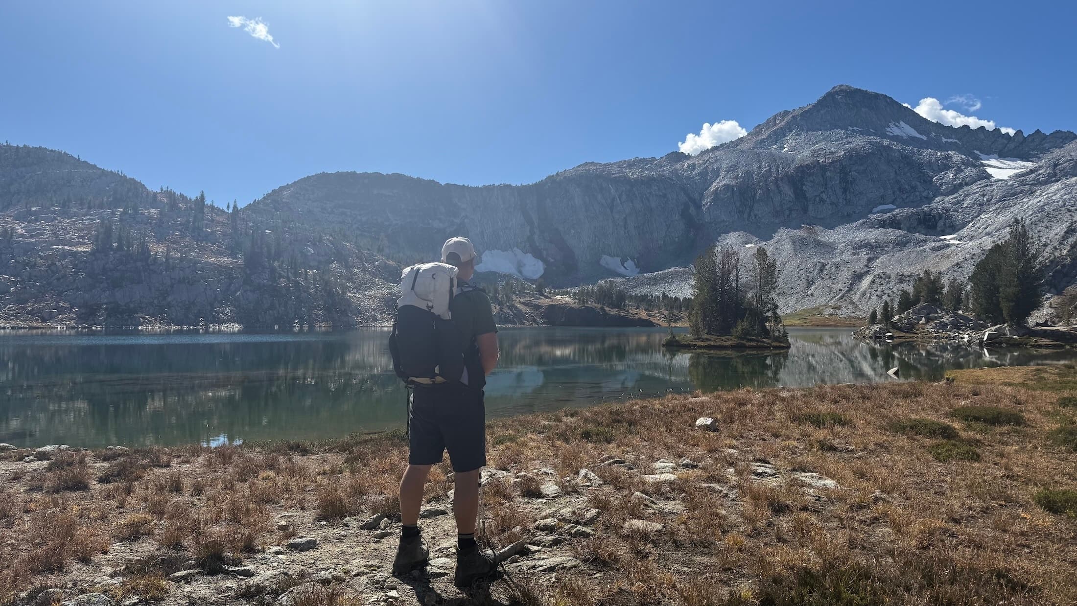 Stephen, seen from behind, wearing the 28-liter UltrAspire Altruist beside an alpine lake in the Eagle Cap Wilderness