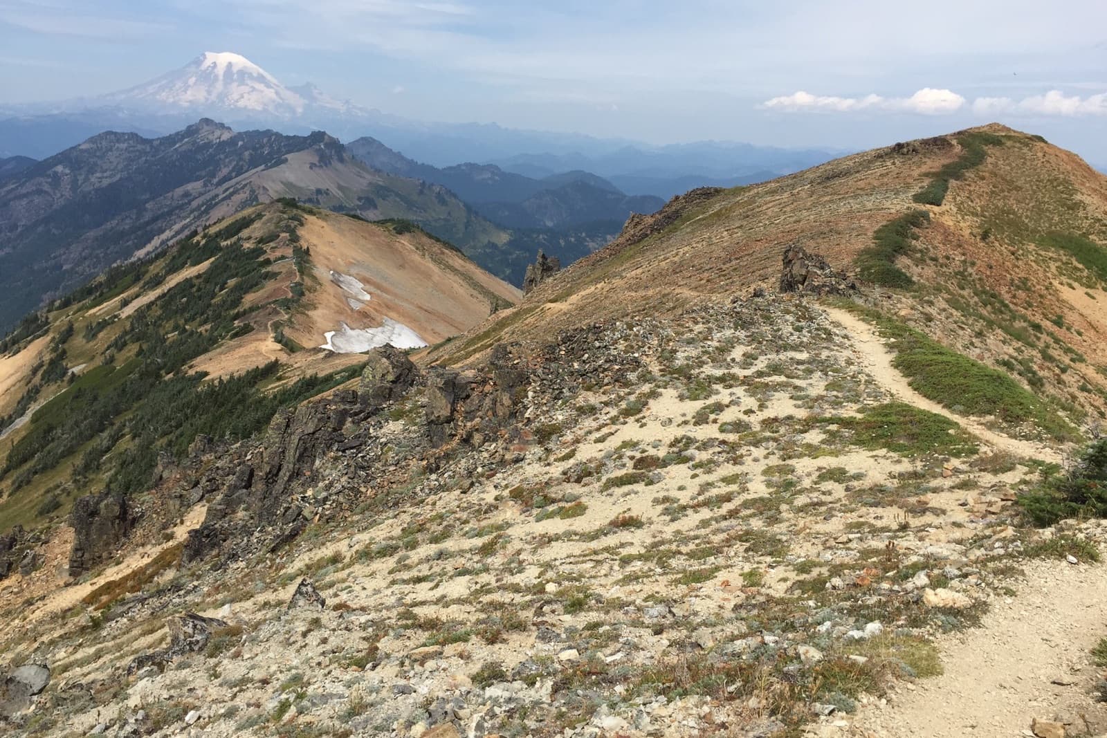 A dry, exposed ridgeline trail in the Goat Rocks Wilderness with Mount Rainier in the distance